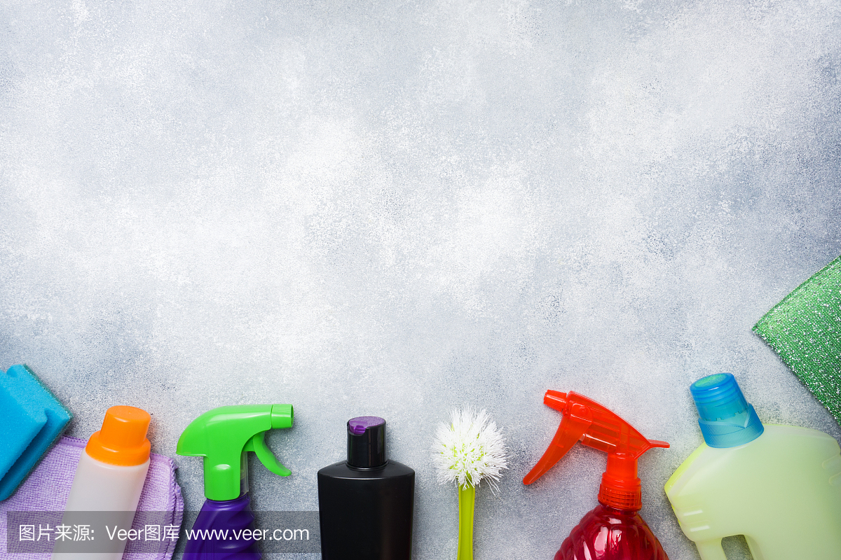 瓶子與洗滌劑,刷子和海綿在混凝土背景。色彩鮮艷的清潔產(chǎn)品。家庭清潔的概念。俯視圖,復(fù)制空間。